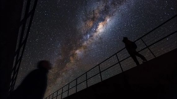 Two people look up at the starry sky from the balconies of the Residencia buildling